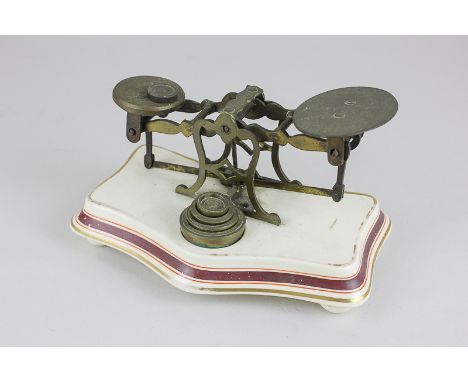A pair of brass postal scales on ceramic base