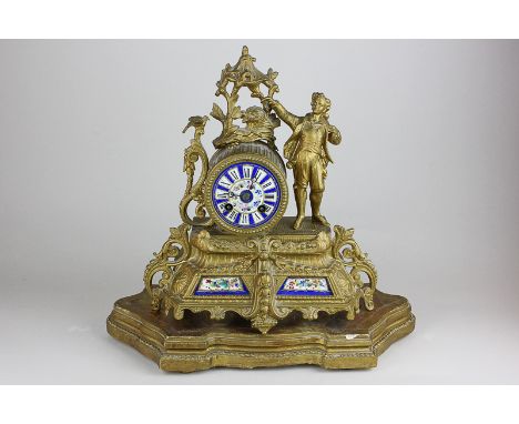 A 19th century French gilded spelter mantel clock with a figure of a young man travelling and a bird in foliage, with blue fl