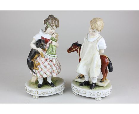 A pair of European porcelain figures of a boy and a girl playing with toys, 20cm high