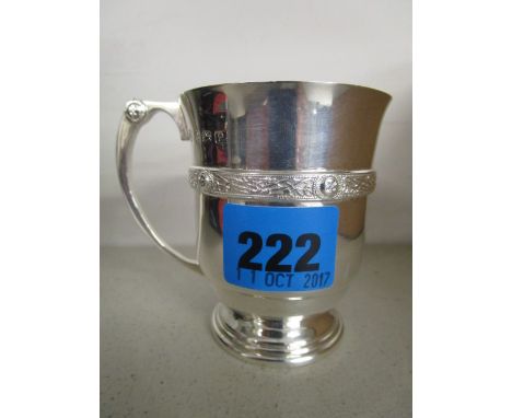 An early 20th century silver handled mug on a raised, stepped foot, a continuous band of Celtic inspired decoration to the bo