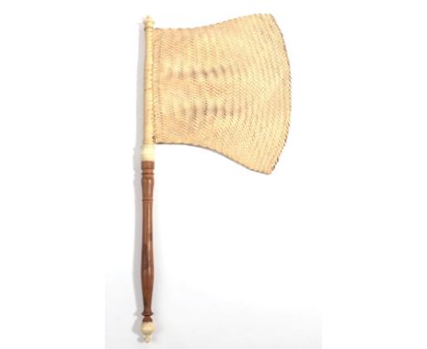 A Shaped Woven Flag Fan, with a turned wood handle and bone or ivory for the finial ends and shoulder, pale fibres woven in b