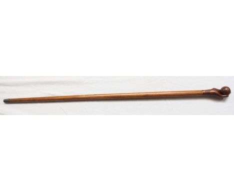 An early 20th century African hardwood walking stick carved with a hand holding a ball