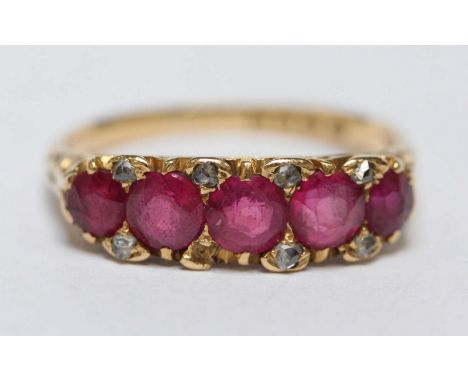 An 18ct gold, diamond and ruby dress ring, set with five central stones surrounded by small diamond chips. 4.3 grams