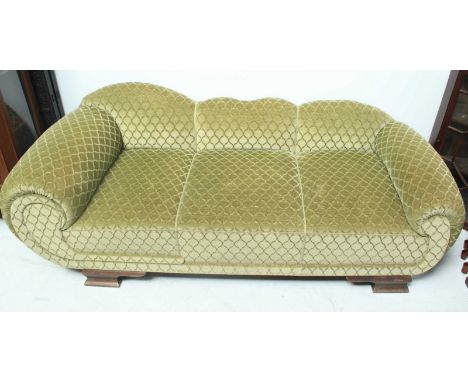 An Art Deco sofa, with scrolled arms and cloud-shaped back, upholstered in a green trellis-patterned plush, on ogee bracket f