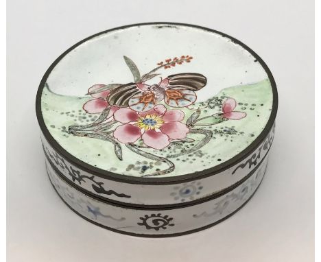 An enamelled patch box decorated with flowers to the top and underside and two gentleman on the interior