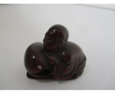 A wooden Netsuke of a male kneeling figure