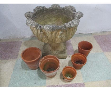 A concrete garden planter along with 5 terracotta pots