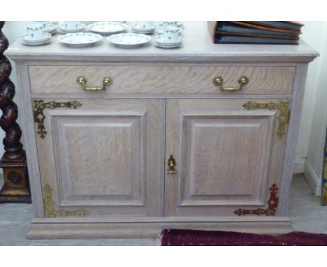 An early 20thC Maple &amp; Co oak, later shabby chic finished sideboard with a long drawer, over two panelled doors, on a pli