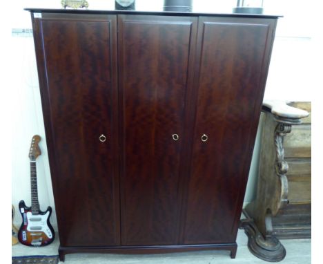 A modern Stag mahogany three door wardrobe with four open shelves and two rails, raised on bracket feet  69''h  53''w      RS