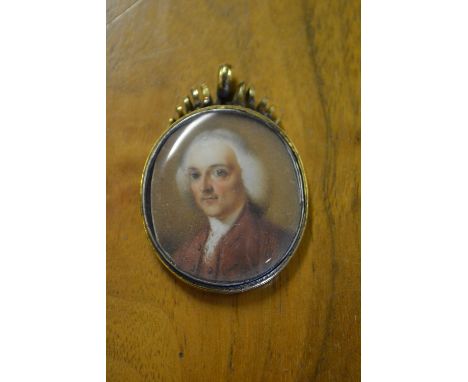 19th Century oval head and shoulder portrait miniature of a bewigged gentleman in red overcoat, in a gold plated housing with
