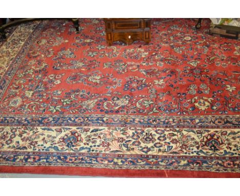 20th Century Saruq carpet with an all-over floral design on a red ground with multiple borders, 14ft x 10ft approximately