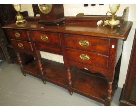 George III oak dresser base, the moulded top above five drawers with oval brass handles, baluster turned supports and pot she