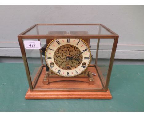 Unusual brass mantelclock with circular brass and light yellow enamel dial inset Roman Numerals all within a glass and brass 