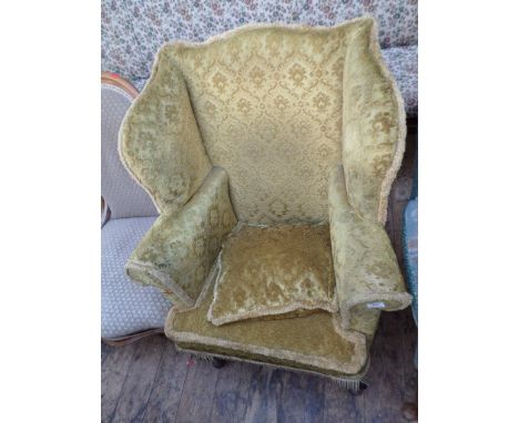 20th century fireside wing armchair on shaped spud feet upholstered in patterned gold fringed contemporary cloth with cushion