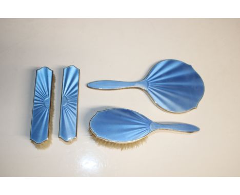 A silver and blue enamel decorated dressing table hand mirror and three brushes 