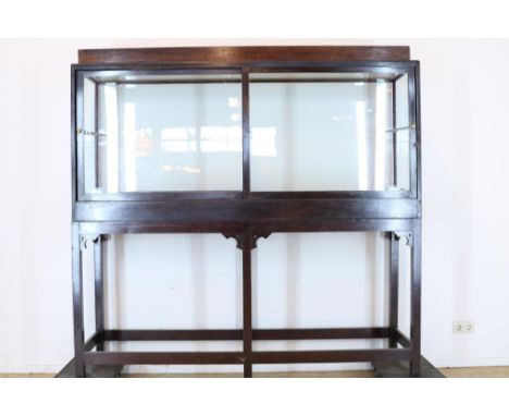 Stained wooden showcase with 2 glass sliding doors and light. H.  193 cm, W. 200 cm, D. 50 cm.Gebeitste houten vitrine met 2 
