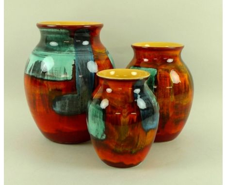 A graduated group of three Poole pottery vases, of baluster form, decorated with abstract design and yellow interiors, larges