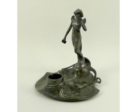 A WMF Art Nouveau pewter figural inkwell, modelled with young maiden reading a book and stood on a rock at the ‘pool’ of her 