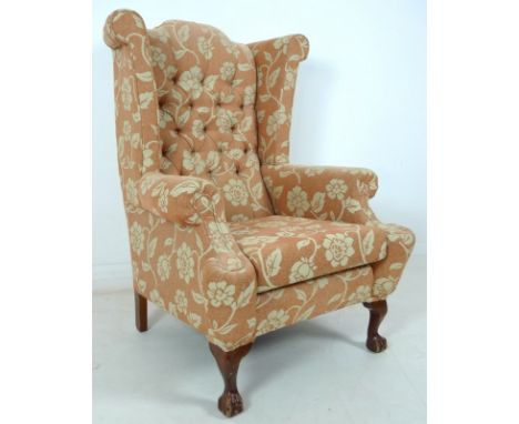 A mid 20th century wing armchair, with carved cabriole legs, upholstered with a salmon coloured button back floral fabric, 83
