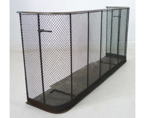An early 20th century brass and wirework fireguard, with integral holders for fire irons, 129 by 33 by 61cm high.