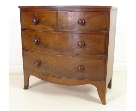 A Regency mahogany bow fronted chest of two short over two long drawers, with turned handles and cock beading, over a shaped 