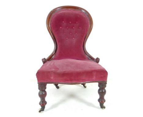 A Victorian mahogany nursing chair, moulded frame, turned front legs and castors, upholstered in button back red velvet, 57 b