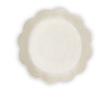 A Chinese Dingyao white-glazed twelve-petal 'floral' dish, Song dynasty, the flat base rising to a gently sloping cavetto div