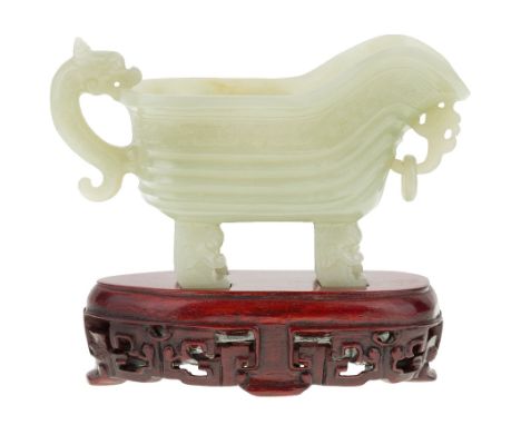 A Chinese celadon jade archaistic pouring vessel, yi, Republic period, supported by four grooved legs with mythical beast mas
