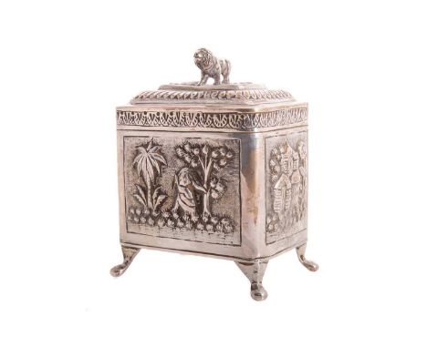 INDIAN WHITE METAL CADDY EARLY 20TH CENTURY  the lid with lion/tiger finial, embossed with panels including trees and archite