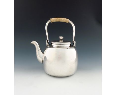 A Japanese silver kettle, by Okubo, panelled circular form, rope-bound swing-handle, the pull-off cover with a stylised chrys