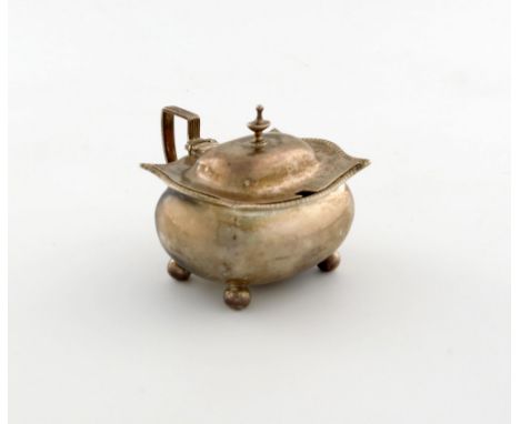 A George III silver mustard pot, maker's mark over-stamped, London 1809, oblong bellied form, reeded scroll handle, gadroon b