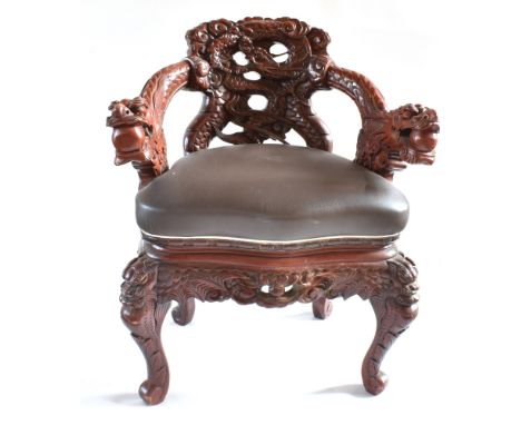 A CHINESE DRAGON-CARVED COMMODE CHAIR with a serpentine front and crabriole legs, 86.5cm high, 72.5cm wide.