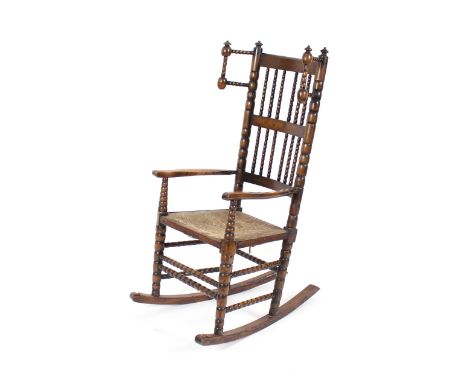 An elm Yorkshire style winged rocking chair, with bobbin railed back and stretchers, rush work seat on turned supports