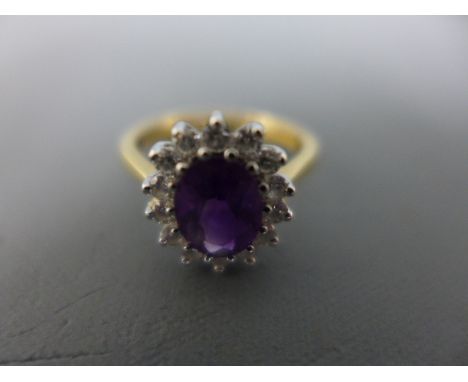 An 18ct gold amethyst and diamond cluster ring - the oval amethyst within a brilliant-cut diamond surround - Hallmarked Londo