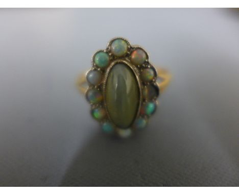 An 18ct yellow gold dress ring with central oval cats eye agate surrounded by opals - size Q - Weight approx. 3.9gmsCondition