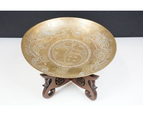 Large brass Chinese bowl with Chinese character symbols and dragon etching on carved wooden display stand. 16cm high, 36cm di
