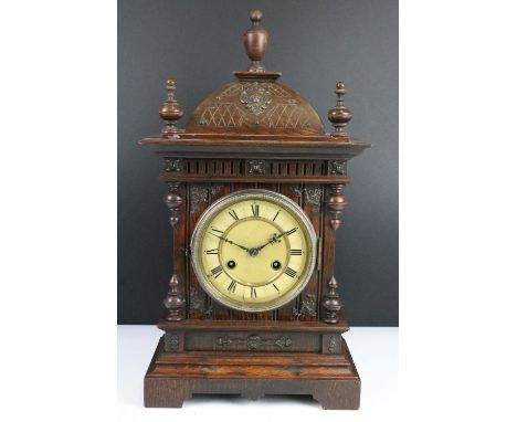 Antique mantel clock with attractive carved wood case, complete with key. 50cm high, 27cm wide and 15cm deep.