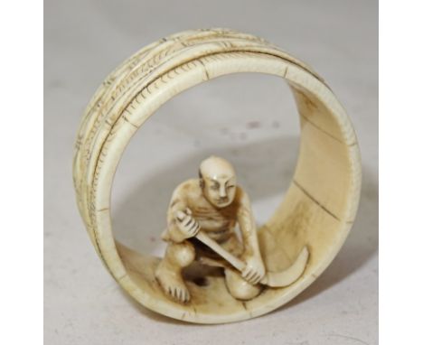 A Japanese bone netsuke
Meiji period
Ring shaped, carved with a bamboo cane motif.. Crouching peasant to the hollow interior.
