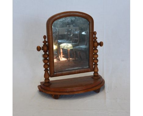 A Victorian mahogany framed dressing table mirror with arched top on bobbin turned supports, plinth base and stylised leaf ca