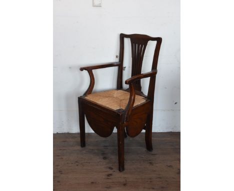 A Georgian oak and elm commode chair with pierced splat back, down-swept arm supports, loose rush seat lifting to reveal a ch