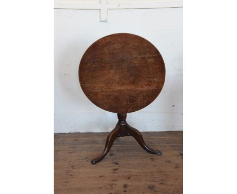 An 18th century oak tripod table with revolving top on a turned stem, tripod legs and pad feet.  28ins diameter.  