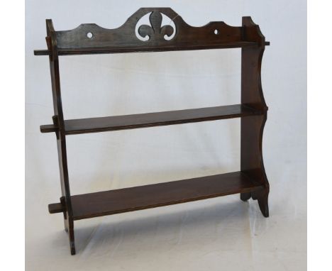 A late Victorian hanging shelf with fleur de lys pierced carved pediment above three shelves on shaped end supports.  26ins w