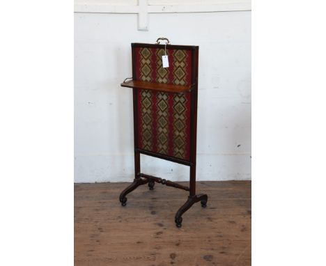 A mid 19th century mahogany fire screen with sliding central section and a small folding central shelf on scroll carved legs,