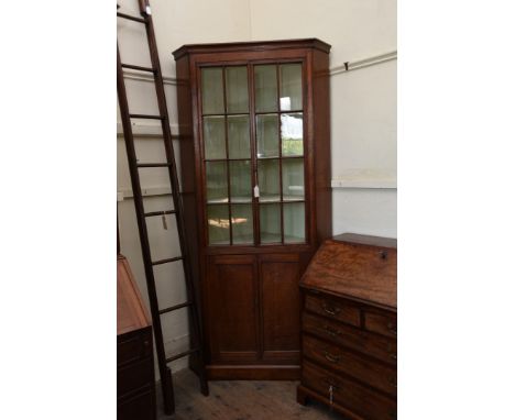 A late George III oak standing corner cupboard with two glazed doors opening to reveal three shaped front interior shelves, t