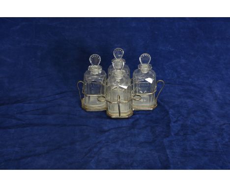 A plated four bottle decanter holder containing four decanters engraved ‘Rum’, ‘Brandy’, ‘Shrub’ and ‘Hollands’.  