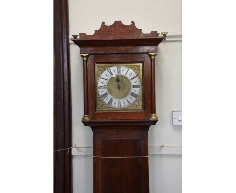 An 18th century oak cased longcase clock, the hood with scroll decorated stepped pediment and demi-pilasters forming the hood