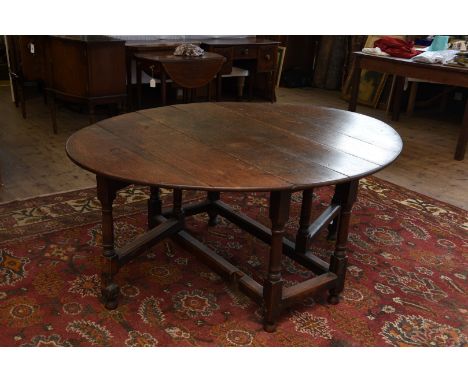 An 18th century oak drop-leaf gate leg table with oval top on turned supports and flattened stretchers.  52ins wide.  