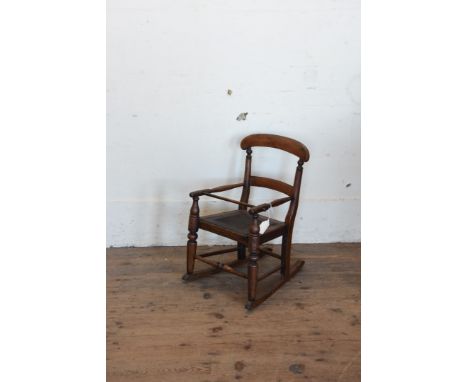 An early 20th century child’s rocking chair with curved cresting rail and splat back, turned arms and arm supports, removable