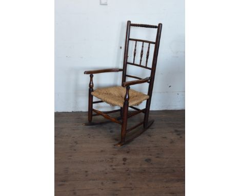 A 19th century elm rocking chair with bobbin turned cresting rail, turned spindle back, shaped arms, turned arm supports, rus