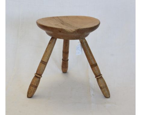 A mid 19th century Welsh milking stool with circular seat on tripod turned out-splayed legs.  